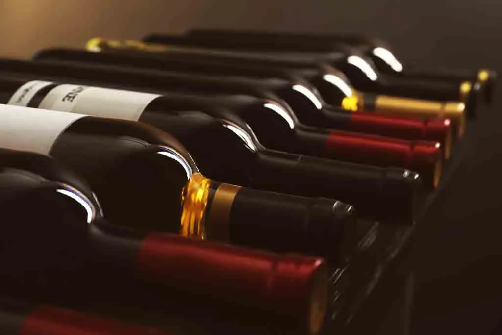 Bottles with delicious wine on shelf, closeup. Professional somm